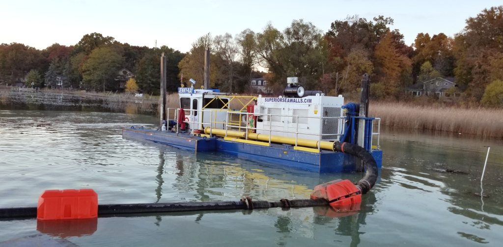 Hydraulic dredging equipment removing sediment from a pond